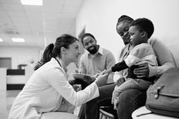 A smiling physician talking with a family in the hallway