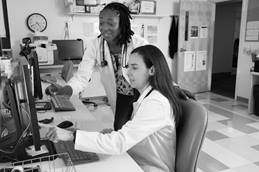 one doctor sitting and one doctor standing looking at a monitor