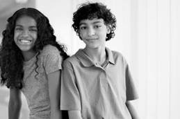 Smiling Tween Girl and Boy Sitting in Hallway