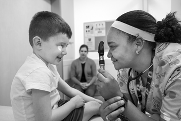 young boy getting eyes checked by a nurse