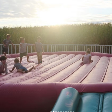 kids jumping on trampoline in a corn field